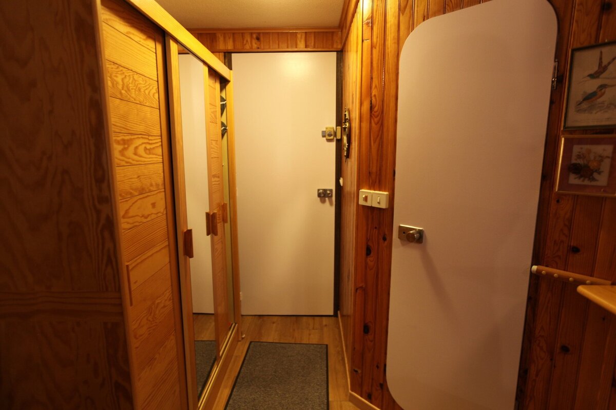 A hallway with wood paneling and a white door