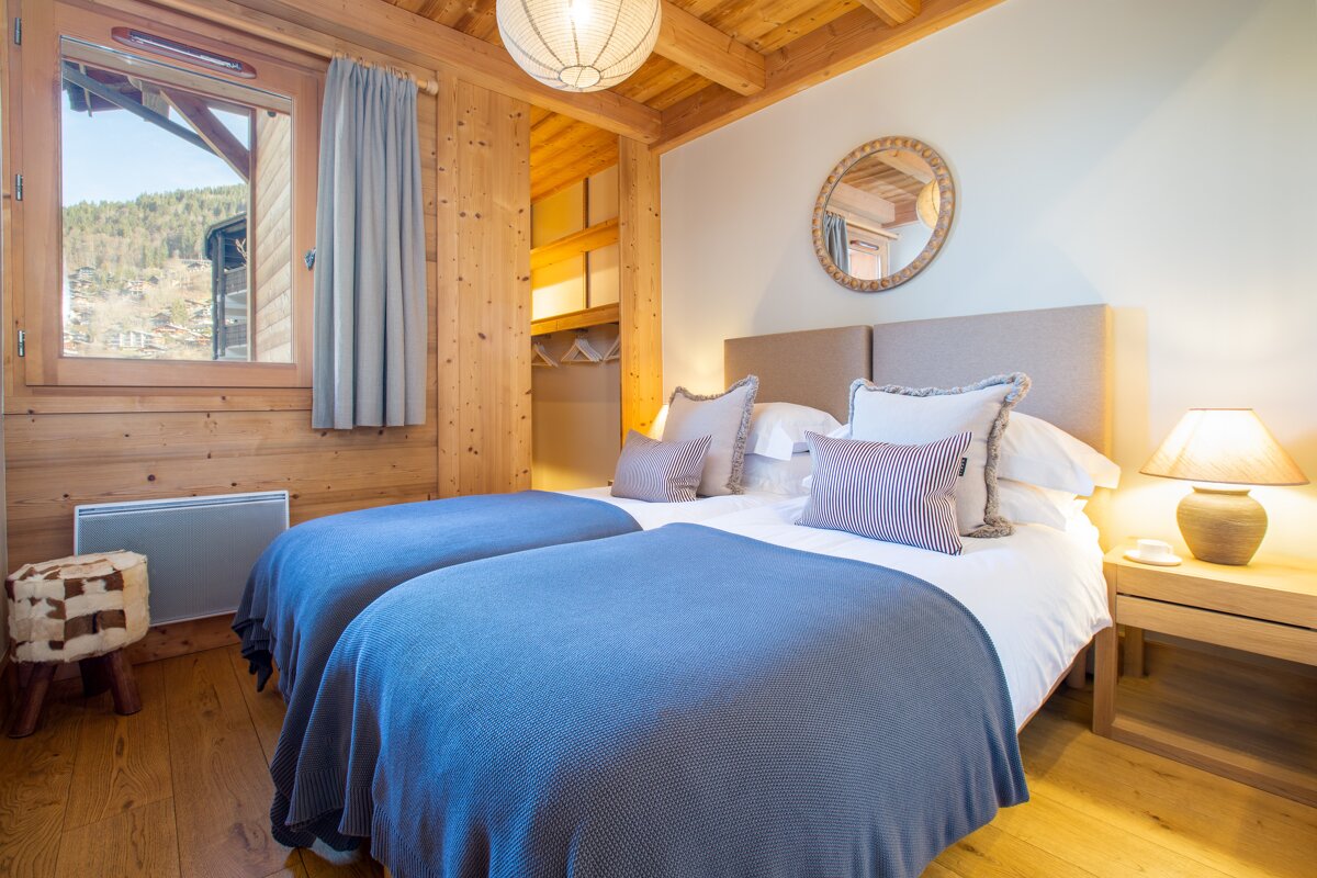 A bedroom with two beds and a mirror on the wall