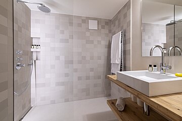 A bathroom with a walk in shower and a sink