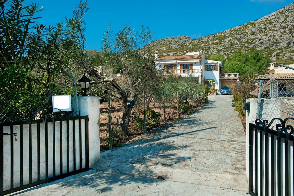 A white house with a blue car parked in front of it