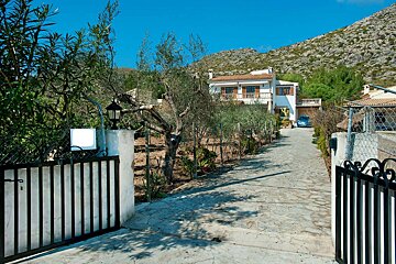 A white house with a blue car parked in front of it
