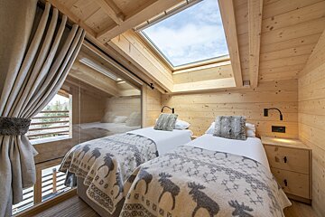 A bedroom with two beds and a skylight