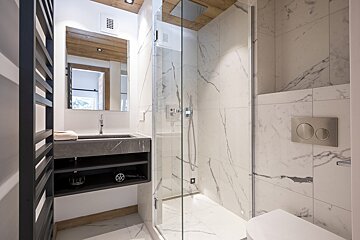 A bathroom with marble tiles and a walk in shower