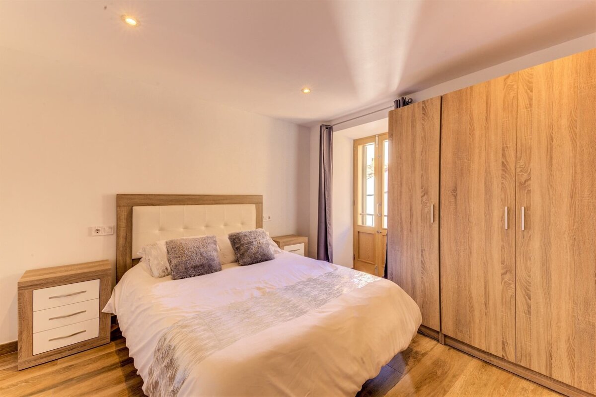 A bedroom with a bed a nightstand and a wardrobe