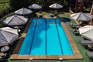 A large swimming pool surrounded by chairs and umbrellas