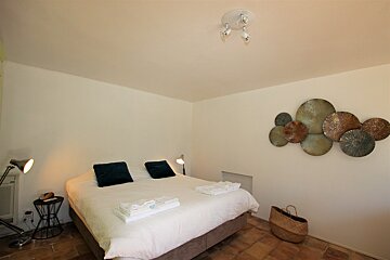 A bedroom with a large bed and a basket on the floor