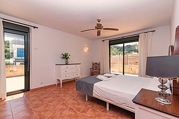 A bedroom with a large bed and a ceiling fan