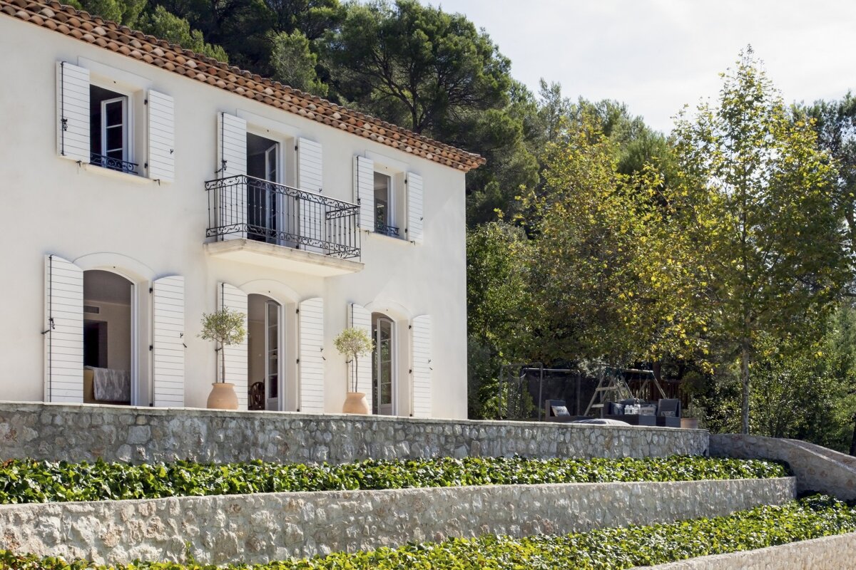 A white house with white shutters and a balcony