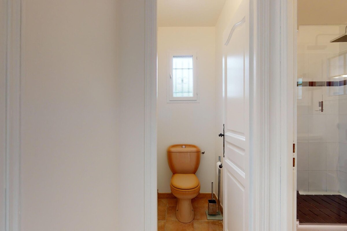 A bathroom with a toilet and a window