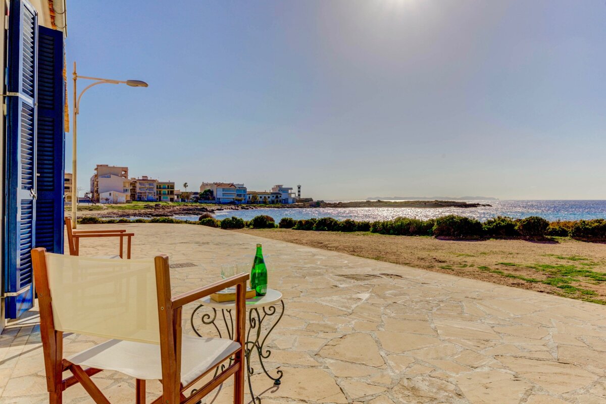 A green bottle sits on a table with a view of the ocean