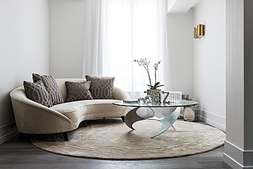 A living room with a curved couch and a glass coffee table
