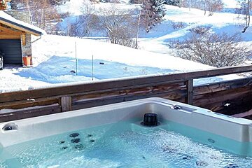 A bmw is parked in the snow next to a hot tub