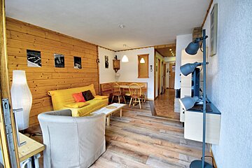 A living room with a yellow couch and a white chair