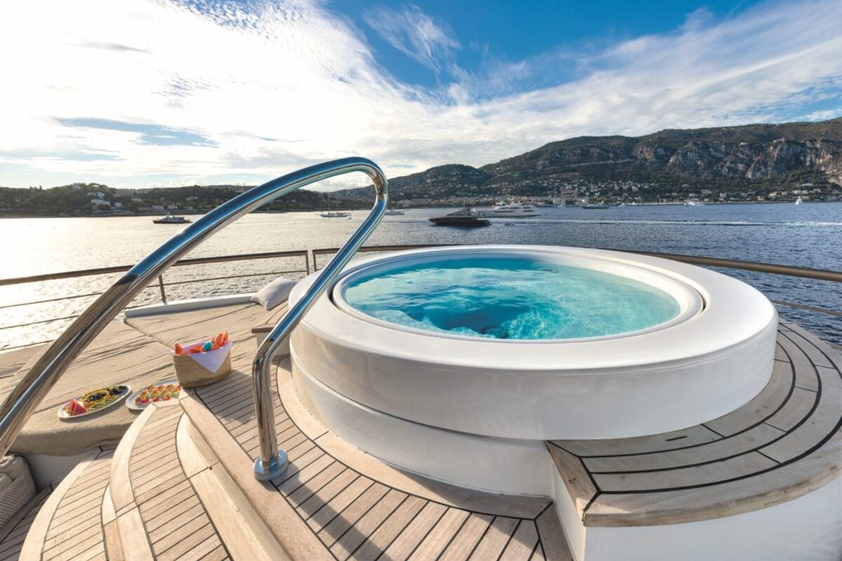 A hot tub on the deck of a boat with mountains in the background
