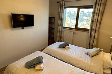 A bedroom with two beds and a flat screen tv