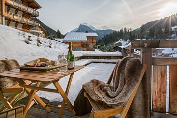 A bottle of champagne sits on a table in the snow