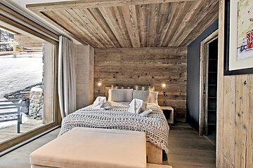 A bedroom with a wooden ceiling and a large window