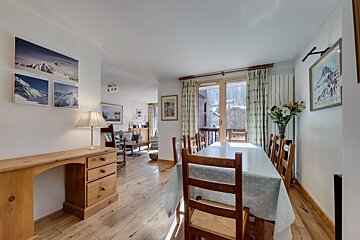 A dining room with a table and chairs and pictures on the wall