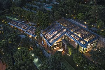 An aerial view of a house surrounded by trees and a pool