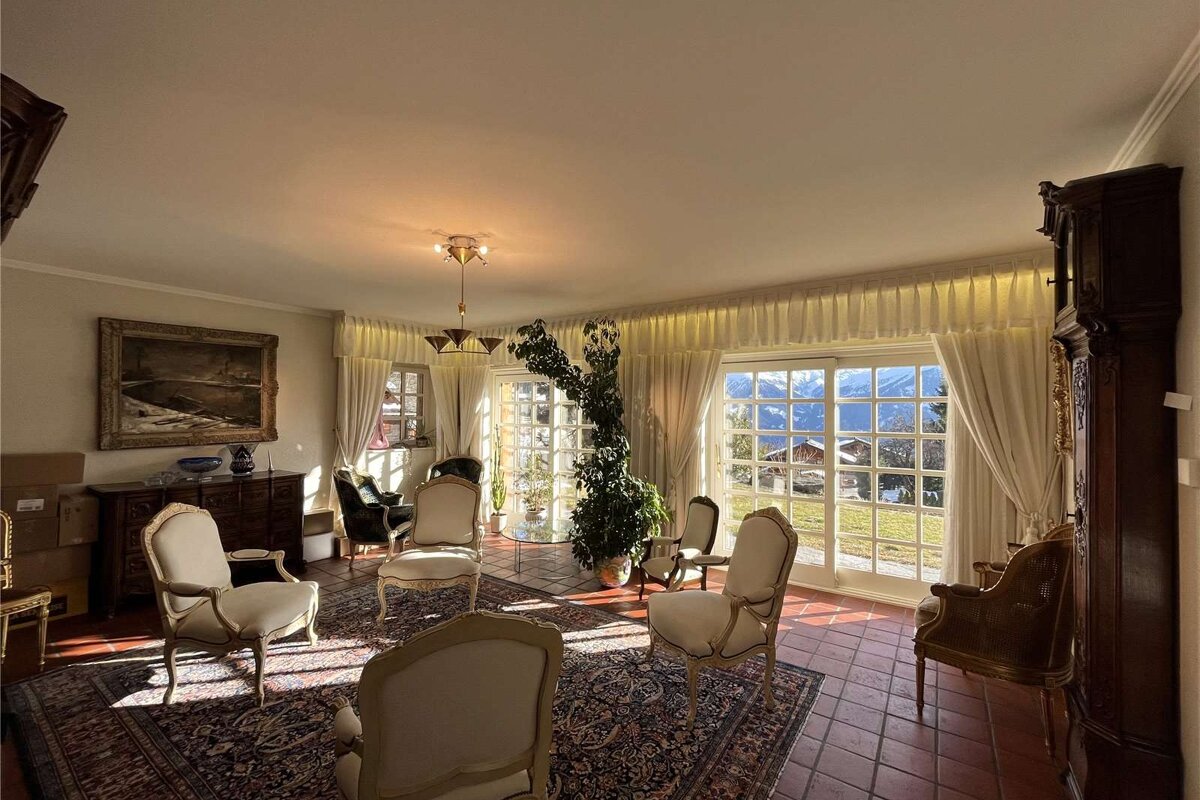 A living room with chairs and a painting on the wall