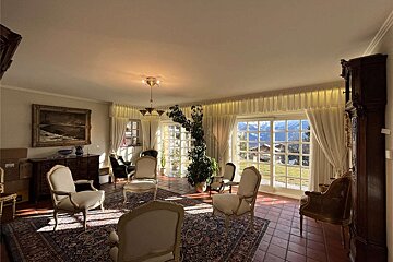 A living room with chairs and a painting on the wall