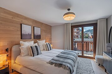 A bedroom with a large bed and a balcony