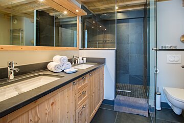 A bathroom with two sinks and a walk in shower