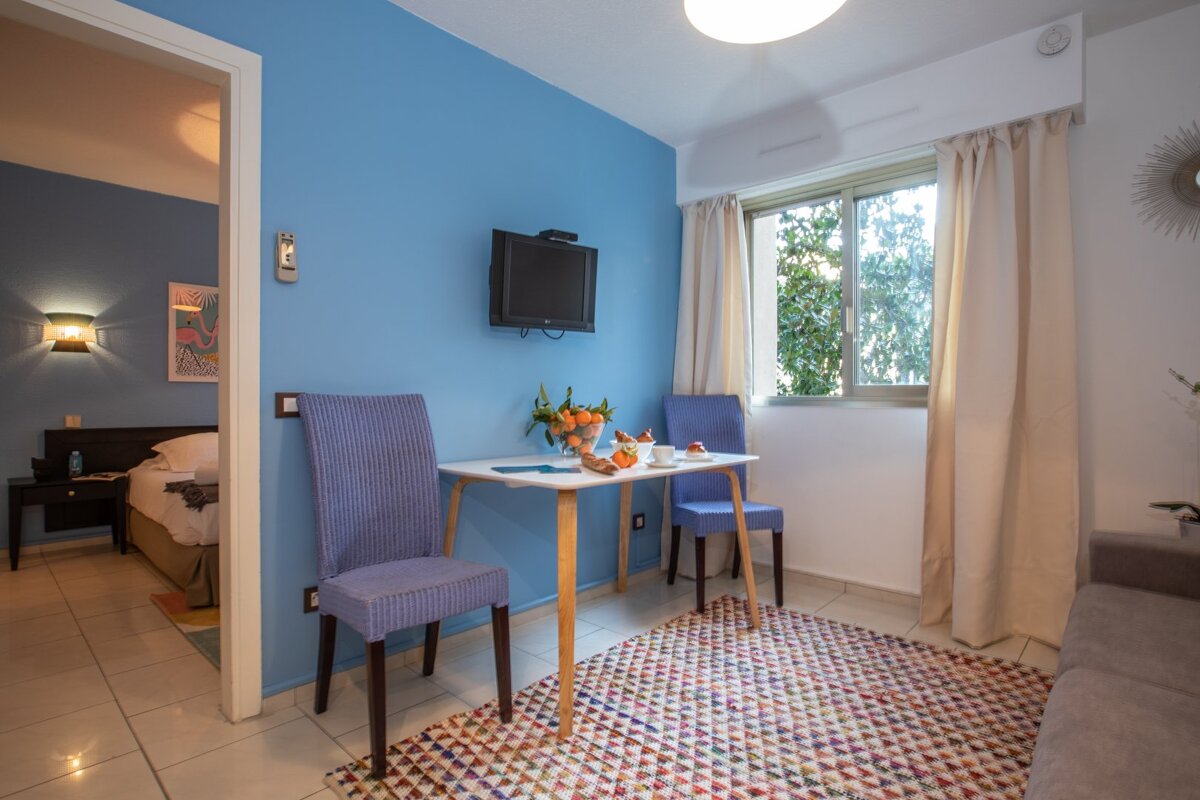 A living room with a table and chairs and a flat screen tv