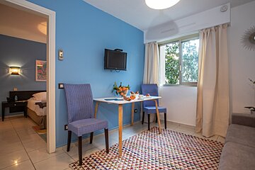 A living room with a table and chairs and a flat screen tv
