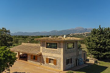 A large stone house with mountains in the background