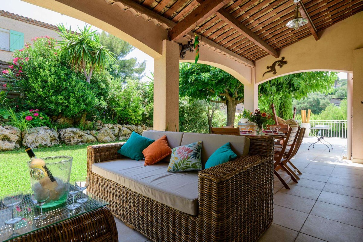 A patio with a couch and a table with a bottle of champagne on it