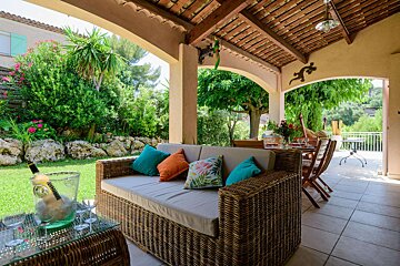 A patio with a couch and a table with a bottle of champagne on it