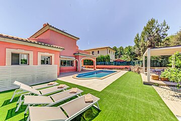 A pink house with a swimming pool in front of it