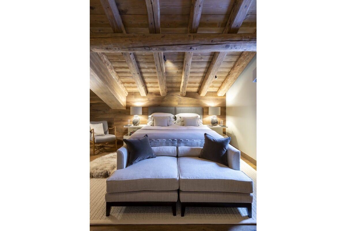 A bedroom with a couch and a bed with wooden beams