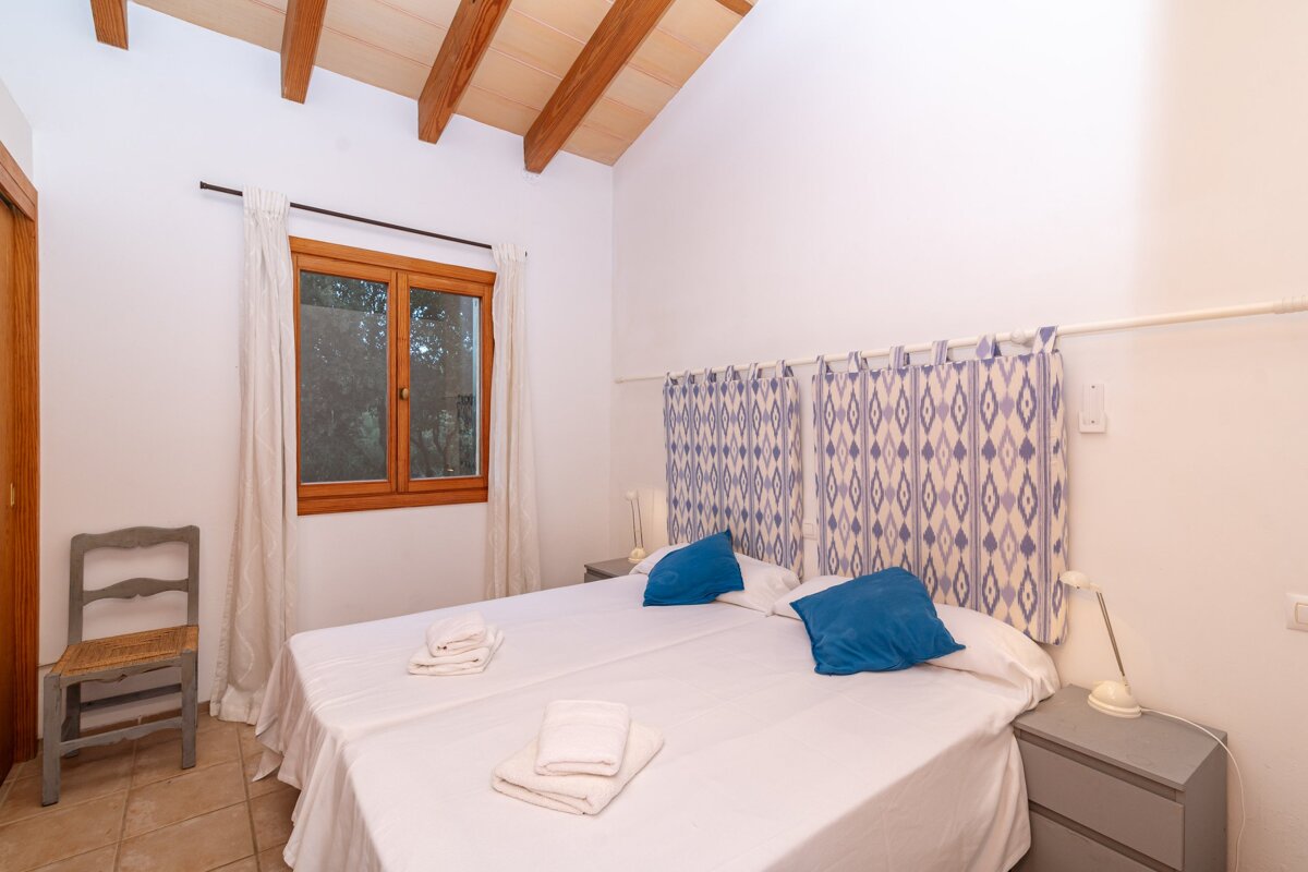 A bedroom with two beds a chair and a window