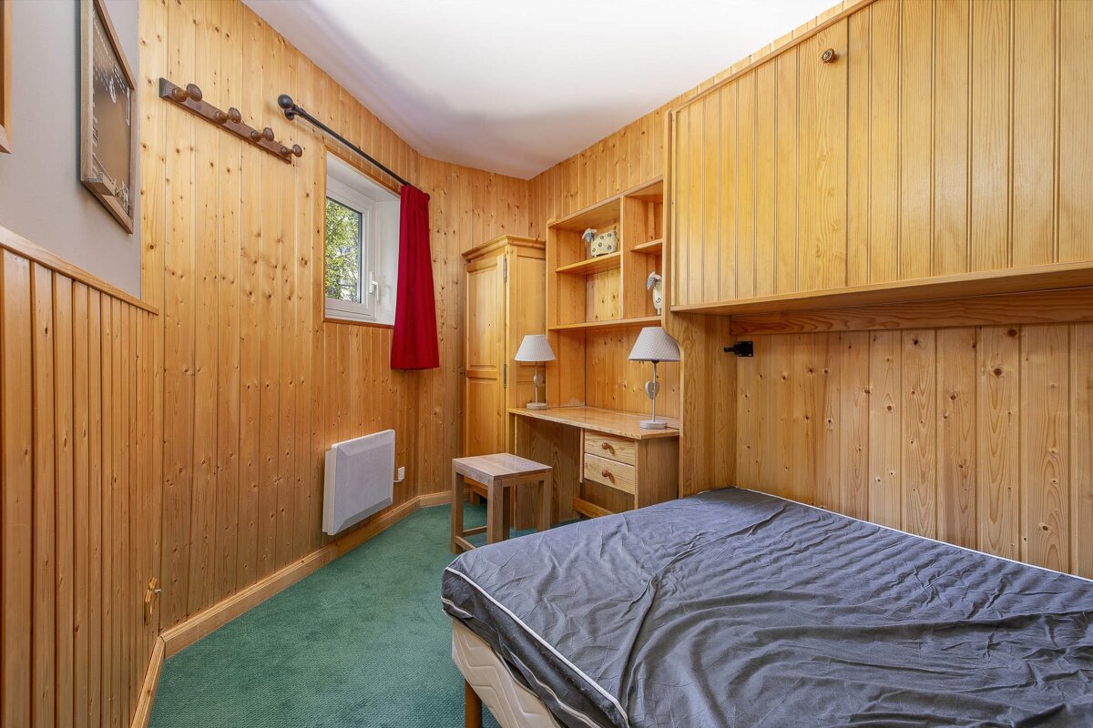 A bunk bed in a small room with a red curtain