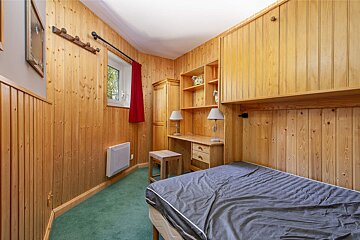 A bunk bed in a small room with a red curtain