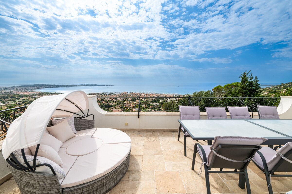 A patio with a couch and a table with a view of the ocean