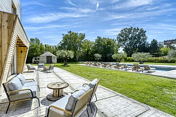 A patio with chairs and a table in front of a pool