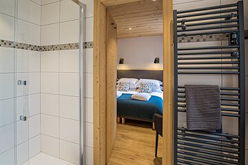 A bedroom with a bed and a towel rack