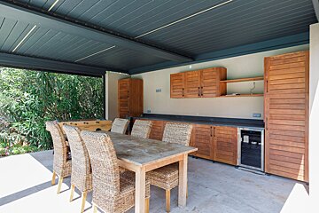 A table with wicker chairs under a blue roof