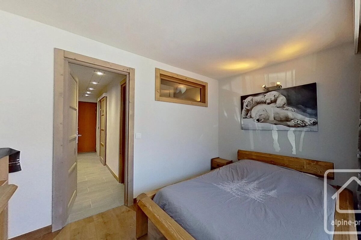 A cozy bedroom with a wooden bed, polar bear painting, and an open doorway leading into a hallway.