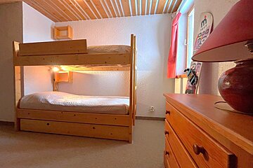 A bedroom with a bunk bed and a dresser