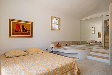 A bedroom with a bathtub and a painting on the wall