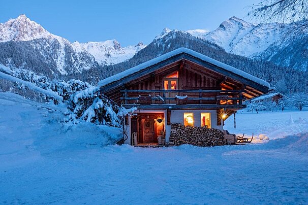 A snowy cabin with mountains in the background