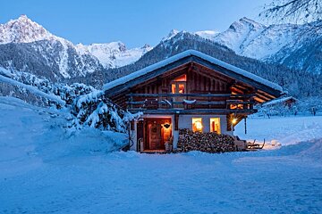 A snowy cabin with mountains in the background