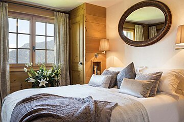 A bedroom with a bed and a mirror above it