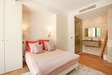 A bedroom with a pink bed and pink pillows