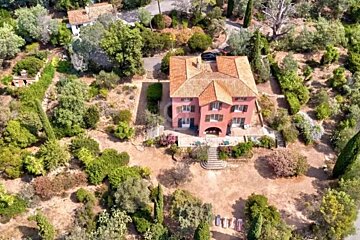 An aerial view of a large house surrounded by trees and bushes