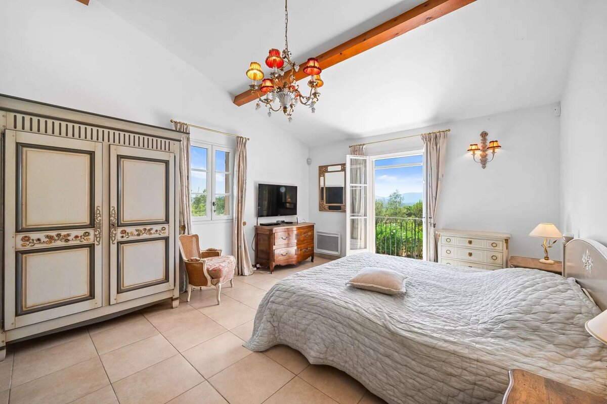 A bedroom with a large bed a dresser and a television